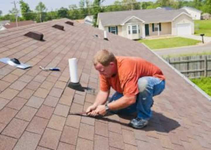 An expert begins pulling up shingles on a damaged roof for roof replacement services in Auburn, AL to begin.